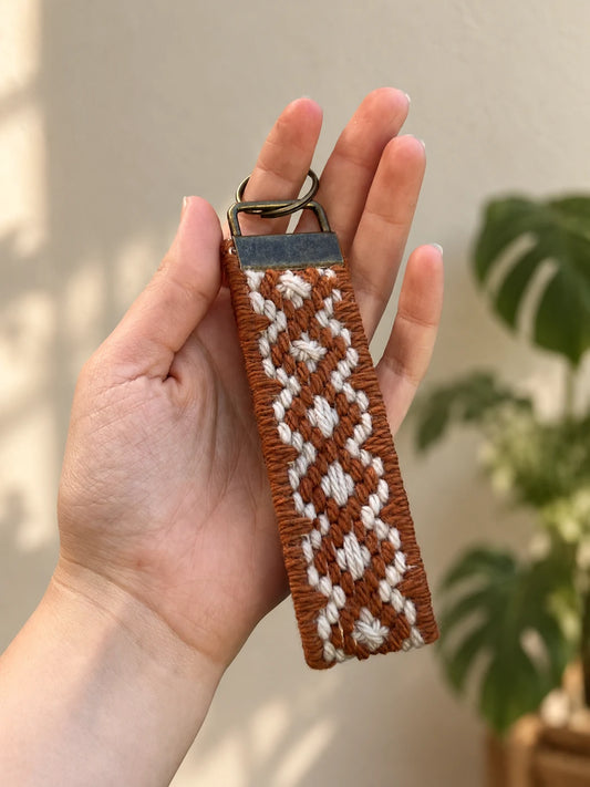 Llavero Franja Ritmo Cobre bordado sobre cañamazo, en Natural y Cobre, en la mano — Ms. Bordados